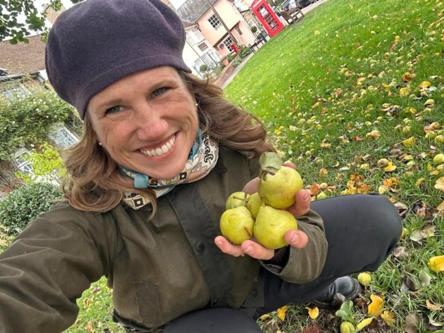 Lisa M. Rose in a beret and scarf holding wild pears gathered from a town green